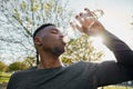 Young black man in sports clothing with closed eyes drinking water from bottle in park Royalty Free Stock Photo