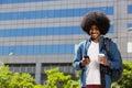 Young black man standing outside with mobile phone and bag Royalty Free Stock Photo