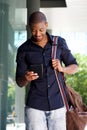 Young black man walking outside with bag and mobile phone Royalty Free Stock Photo