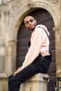 Young black man wearing casual clothes and sunglasses sitting on the street Royalty Free Stock Photo