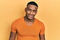 Young black man wearing casual orange t shirt looking positive and happy standing and smiling with a confident smile showing teeth Royalty Free Stock Photo