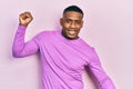 Young black man wearing casual pink sweater dancing happy and cheerful, smiling moving casual and confident listening to music Royalty Free Stock Photo