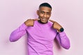 Young black man wearing casual pink sweater smiling cheerful showing and pointing with fingers teeth and mouth