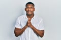 Young black man wearing casual white shirt begging and praying with hands together with hope expression on face very emotional and Royalty Free Stock Photo