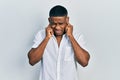 Young black man wearing casual white shirt covering ears with fingers with annoyed expression for the noise of loud music Royalty Free Stock Photo