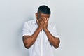 Young black man wearing casual white shirt with sad expression covering face with hands while crying Royalty Free Stock Photo