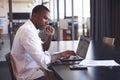 Young black man in wearing glasses using laptop in office