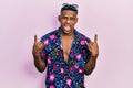 Young black man wearing hawaiian shirt and sunglasses shouting with crazy expression doing rock symbol with hands up Royalty Free Stock Photo