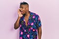 Young black man wearing hawaiian shirt and sunglasses shouting and screaming loud to side with hand on mouth Royalty Free Stock Photo