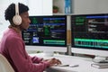 Young Black Man Wearing Headphones Coding on Computer Monitors in Office Royalty Free Stock Photo