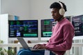 Young Black Man Wearing Headphones Working on Laptop in Office Royalty Free Stock Photo