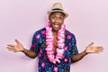 Young black man wearing summer shirt and hawaiian lei celebrating victory with happy smile and winner expression with raised hands Royalty Free Stock Photo