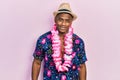Young black man wearing summer shirt and hawaiian lei looking positive and happy standing and smiling with a confident smile Royalty Free Stock Photo