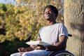 Young Black man in wheelchair enjoying snack in park Royalty Free Stock Photo