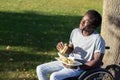 Young Black man in wheelchair having lunch in city park Royalty Free Stock Photo