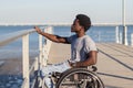 Young Black man in wheelchair looking at seascape