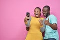 young black man and woman feeling excited and happy viewing content on a mobile phone together, giving thumbs up gesture Royalty Free Stock Photo