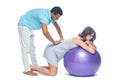 A young black man helps his white wife with birth pain with a ball. Partnered birth, partnered delivery. Isolated white