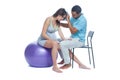 A young black man helps his white wife with birth pain with a ball. Partnered birth, partnered delivery. Isolated white