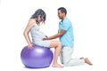 A young black man helps his white wife with birth pain with a ball. Partnered birth, partnered delivery. Isolated white