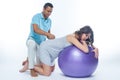 A young black man helps his white wife with birth pain with a ball. Partnered birth, partnered delivery. Isolated white