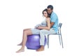 A young black man helps his white wife with birth pain with a ball. Partnered birth, partnered delivery. Isolated white