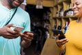 a young black man paying in a supermarket by doing a transfer with his mobile phone also holding his credit card Royalty Free Stock Photo