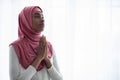 Young Black Muslim Woman In Pink Hijab Praying To Allah With Clasped Hands Royalty Free Stock Photo