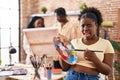 Young black painter woman at art studio holding palette clueless and confused expression Royalty Free Stock Photo