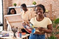 Young black painter woman at art studio holding palette smiling with a happy and cool smile on face Royalty Free Stock Photo