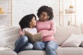 Young black pregnant mother reading book to her daughter at home Royalty Free Stock Photo