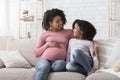 Young black pregnant woman bonding with her little daughter at home