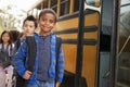 Young black schoolboy and friends wait to get on school bus Royalty Free Stock Photo