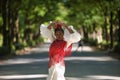 Young black and South American woman in a beige gypsy flamenco suit and red shawl, dancing in a park in the city of Seville in Royalty Free Stock Photo