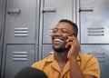 A young black student laughs on a phone call in front of campus lockers