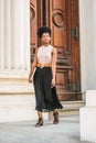 Young black woman with afro hairstyle working in New York, wearing sleeveless light color top, black skirt, belt, strappy sandals Royalty Free Stock Photo