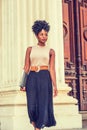 Young black woman with afro hairstyle working in New York, wearing sleeveless light color top, black skirt, dark orange belt, Royalty Free Stock Photo