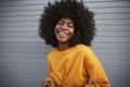 Young African American woman with afro standing against grey security shutters, laughing to camera, close up Royalty Free Stock Photo