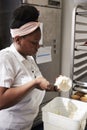 Young black woman at a bakery preparing cake frosting