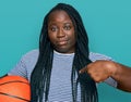 Young black woman with braids holding basketball ball pointing finger to one self smiling happy and proud Royalty Free Stock Photo