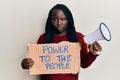 Young black woman with braids holding power to the people banner and megaphone depressed and worry for distress, crying angry and