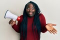 Young black woman with braids shouting through megaphone celebrating achievement with happy smile and winner expression with