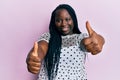 Young black woman with braids wearing casual clothes approving doing positive gesture with hand, thumbs up smiling and happy for Royalty Free Stock Photo