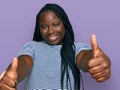 Young black woman with braids wearing casual clothes approving doing positive gesture with hand, thumbs up smiling and happy for Royalty Free Stock Photo