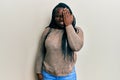 Young black woman with braids wearing casual clothes and glasses covering one eye with hand, confident smile on face and surprise Royalty Free Stock Photo