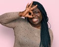 Young black woman with braids wearing casual clothes and glasses smiling happy doing ok sign with hand on eye looking through Royalty Free Stock Photo