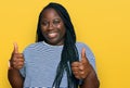 Young black woman with braids wearing casual clothes success sign doing positive gesture with hand, thumbs up smiling and happy Royalty Free Stock Photo