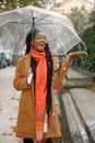 Young black woman in a coat standing under a transparent umbrella outside Royalty Free Stock Photo