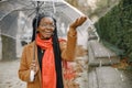 Young black woman in a coat standing under a transparent umbrella outside Royalty Free Stock Photo