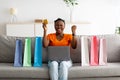 Young black woman with credit card and laptop buying via internet at home, making YES gesture. Online shopping Royalty Free Stock Photo